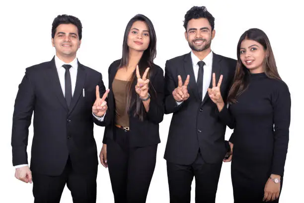 istockphoto-1188020580-612×612 Line of business people standing and showing victory sign on white background. They are wearing formals.